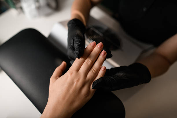 Professional manicurist applying nail polish to client's nails in a salon