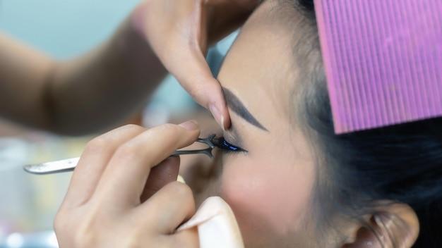 Makeup artist applying eyeliner to a woman's eye